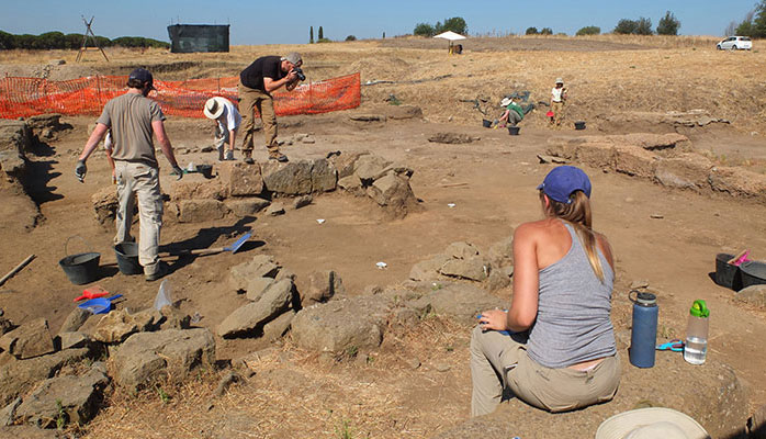 A photograph of four archaeologists digging at the Gabii site.