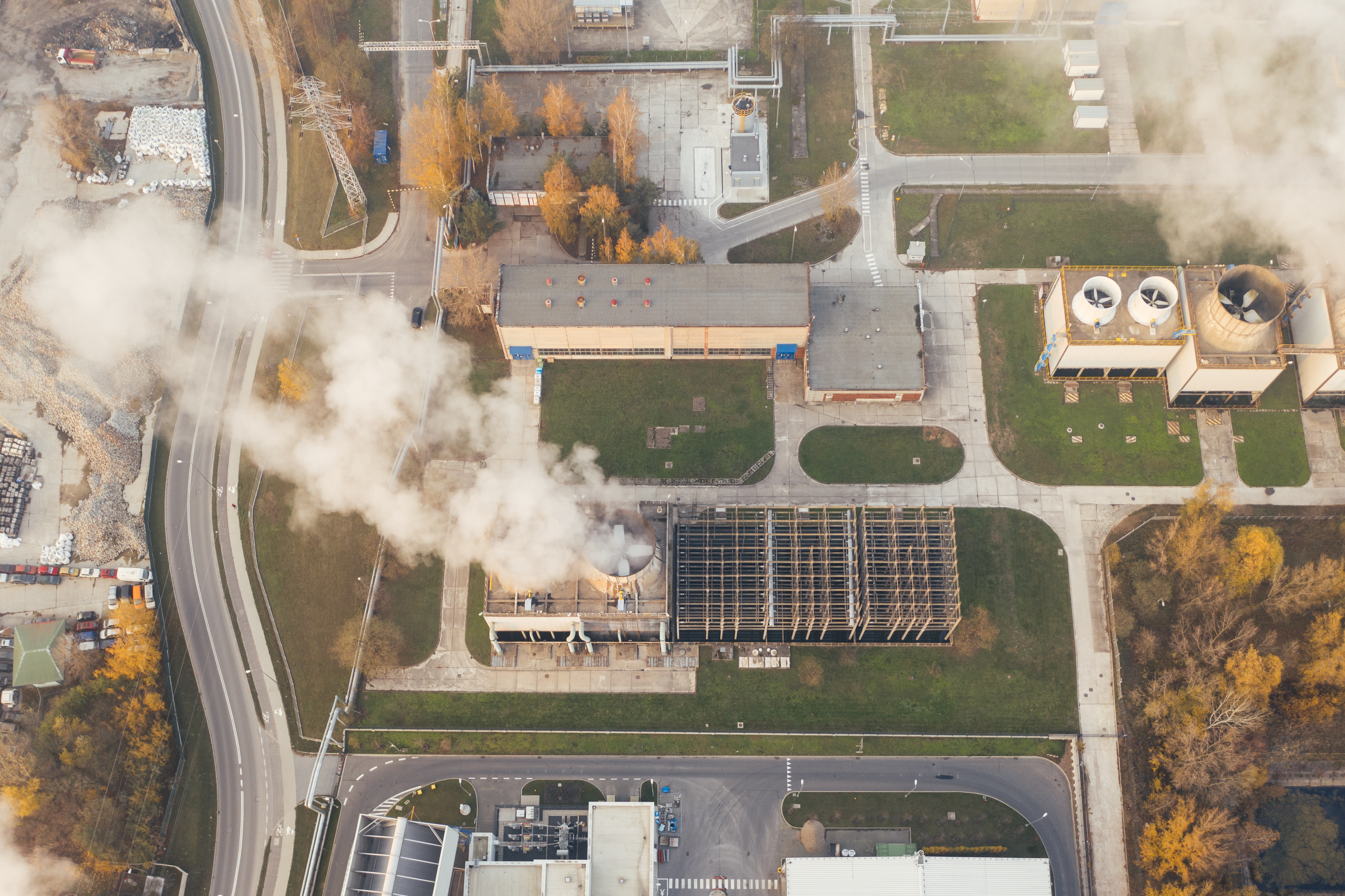An overhead view of factory, with large smoke stacks producing clouds. 